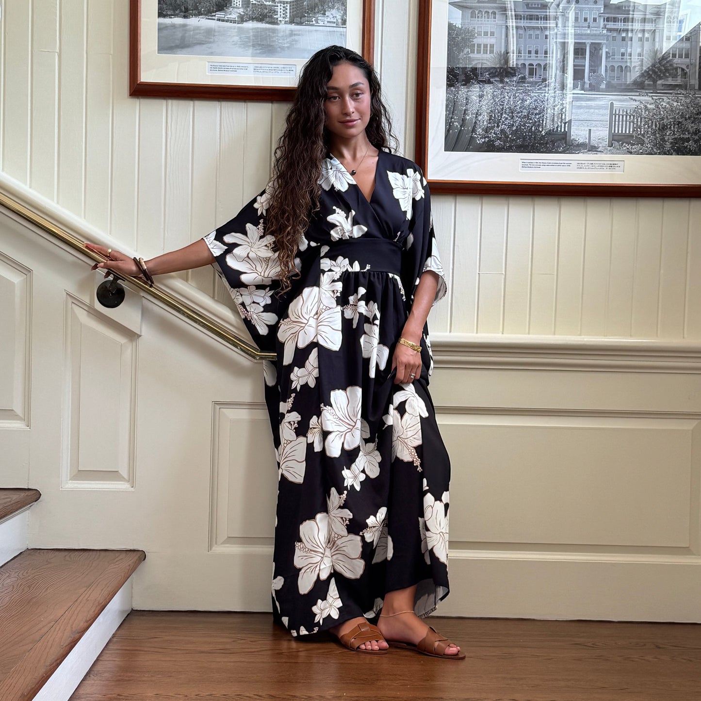 Guava & Co Poema Island Gown in black with white floral print. Features a V-neck, cinched waist, and waterfall back.